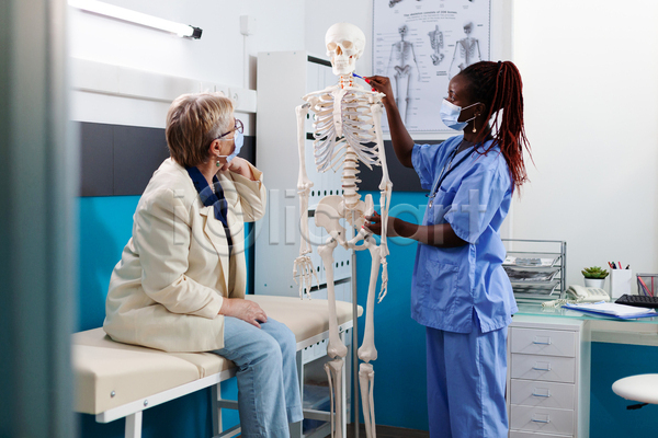 두명 백인 성인 여자 여자만 중년 흑인 JPG 앞모습 포토 해외이미지 들기 뼈모형 상반신 설명 실내 앉기 의료진 의사 환자