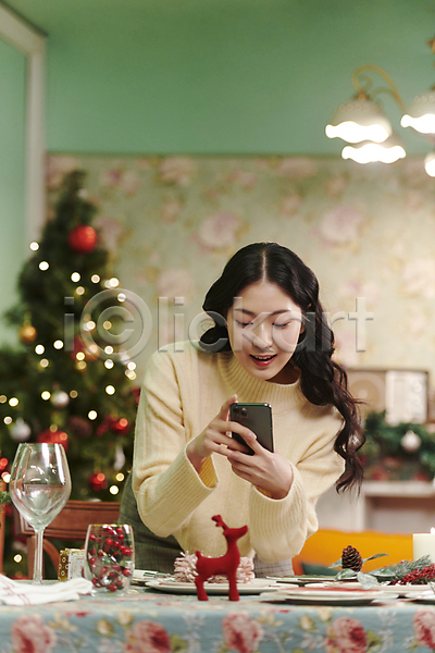 20대 성인 성인여자한명만 여자 한국인 한명 JPG 아웃포커스 앞모습 포토 들기 사진촬영 상반신 스마트폰 실내 우먼라이프 웃음 크리스마스 파티