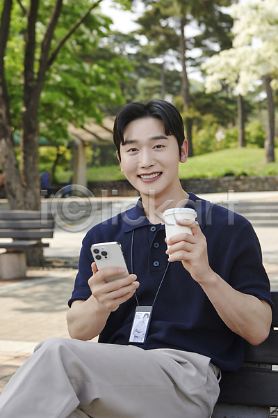 여유 휴식 20대 남자 성인 성인남자한명만 한국인 한명 JPG 앞모습 포토 공원 들기 미소(표정) 벤치 비즈니스라이프 비즈니스맨 사원증 상반신 스마트폰 앉기 야외 주간 직장인 커피 테이크아웃컵
