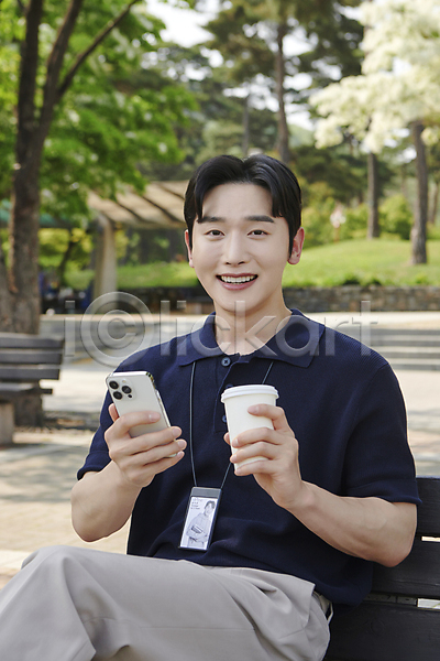 여유 휴식 20대 남자 성인 성인남자한명만 한국인 한명 JPG 앞모습 포토 공원 들기 미소(표정) 벤치 비즈니스라이프 비즈니스맨 사원증 상반신 스마트폰 앉기 야외 주간 직장인 커피 테이크아웃컵
