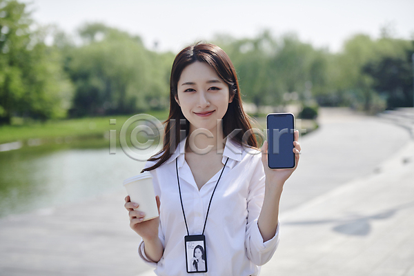 20대 성인 성인여자한명만 여자 한국인 한명 JPG 아웃포커스 앞모습 포토 공원 긍정적 들기 미소(표정) 보여주기 비즈니스라이프 비즈니스우먼 사원증 상반신 스마트폰 야외 주간 직장인 커피 테이크아웃컵