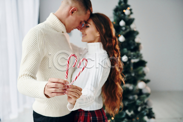 사랑 행복 남자 두명 성인 성인만 여자 JPG 옆모습 포토 해외이미지 겨울 마주보기 보여주기 보케 상반신 장식 지팡이사탕 커플 크리스마스 크리스마스트리