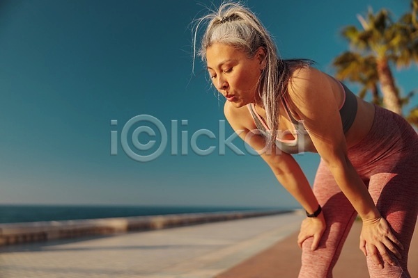 행복 휴식 동양인 성인 여자 한명 JPG 포토 해외이미지 가로 개성 건강 날씬함 달리기 라이프스타일 레깅스 마라톤 바다 뷰티 서기 손목시계 스포츠 신체 야외 에너지 연습 운동 일몰 자극 조깅 해외202309 햇빛 혼자