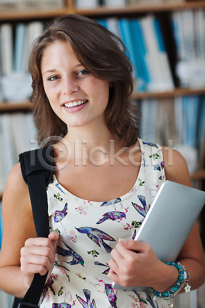 스마트 백인 여자 한명 JPG 포토 해외이미지 가방 갈색머리 교과서 교육 대학교 도서관 미소(표정) 서기 스터디 실내 응시 잡기 정보 짧은머리 책 책장 태블릿 터치스크린 학교 학생 학습 해외202004