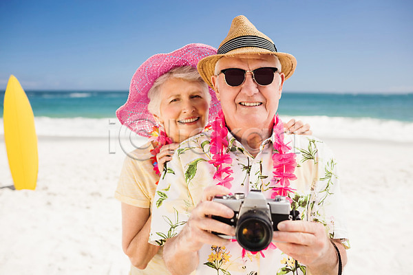 사랑 함께함 행복 70대 남자 노년 노인만 두명 백인 여자 JPG 포토 해외이미지 노후 디지털카메라 맑음 모래 물 미소(표정) 밀짚모자 바다 사진촬영 선글라스 야외 여름(계절) 잡기 커플 파도 파란색 하늘 해외202004 햇빛 휴가