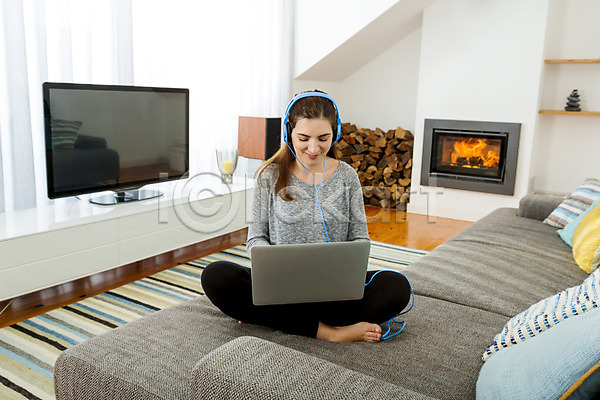 따뜻함 행복 백인 사람 한명 JPG 포토 해외이미지 겨울 노트북 듣기 라이프스타일 리빙 방 벽난로 소파 실내 앉기 음악 읽기 장식 주택 해외202004 헤드폰