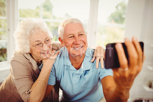 함께함 행복 70대 남자 노년 노인만 두명 백인 여자 JPG 포토 해외이미지 가정 노후 라이프스타일 미소(표정) 보여주기 스마트폰 스크린 실내 아파트 잡기 주택 커플 포즈 해외202004