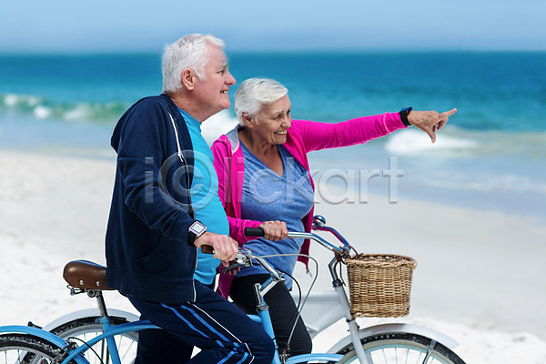 기쁨 평화 함께함 행복 70대 남자 노년 노인만 두명 백인 여자 JPG 포토 해외이미지 가리킴 건강 노후 도전 라이프스타일 맑음 모래 모험가 물 미소(표정) 바다 보여주기 사이클링 스포츠 승차 여름(계절) 자전거 장비 커플 파도 해외202004 휴가