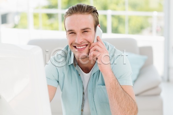 행복 20대 남자 백인 한명 JPG 포토 해외이미지 모니터 무선전화기 무선통신 미소(표정) 비즈니스맨 사무실 스마트폰 스크린 실내 앉기 전화기 직장 책상 키보드 해외202004 핸드폰