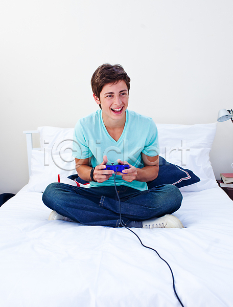 행복 흥분 10대 남자 백인 사람 소년 소년한명만 한명 JPG 포토 해외이미지 가족 게임 놀이 미소(표정) 비디오게임 시스템 실내 앉기 주간 집콕 침대 침실 컴퓨터 테크노 표현 해외202004