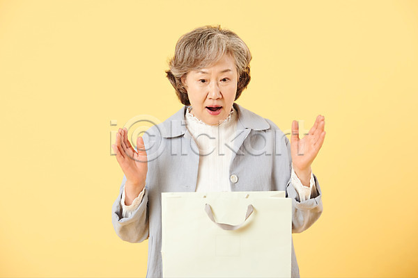 즐거움 60대 노년 노인여자한명만 여자 한국인 한명 JPG 앞모습 포토 노란배경 놀람 뉴식스티 상반신 서기 선물 세일 쇼핑 쇼핑백 스튜디오촬영 실내 실버라이프 액티브시니어 오팔세대 이벤트 캐주얼 할머니