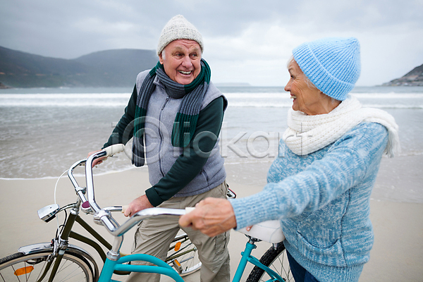 사랑 함께함 70대 남자 노년 노인만 백인 여자 JPG 옆모습 포토 해외이미지 겨울 노부부 대화 라이프스타일 미소(표정) 바다 상반신 서기 응시 자전거 커플 해변 해외202007