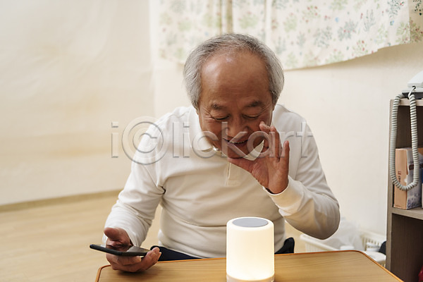 70대 남자 노년 노인남자한명만 한국인 한명 JPG 앞모습 포토 AI(인공지능) 고령화 독거노인 들기 말하기 상반신 손짓 스마트폰 스피커 실내 실버라이프 앉기 할아버지