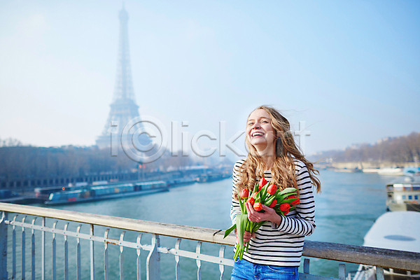 백인 성인 성인여자한명만 여자 한명 JPG 아웃포커스 포토 해외이미지 거리 기댐 꽃다발 들기 미소(표정) 상반신 야외 에펠탑 주간 철제난간 튤립 파리(프랑스)