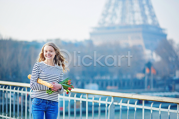백인 성인 성인여자한명만 여자 한명 JPG 아웃포커스 앞모습 포토 해외이미지 거리 꽃다발 들기 미소(표정) 바게트 상반신 야외 에펠탑 주간 튤립 파리(프랑스)