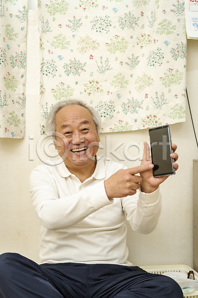 기쁨 70대 남자 노년 노인남자한명만 한국인 한명 JPG 앞모습 포토 가리킴 독거노인 들기 미소(표정) 보여주기 상반신 스마트폰 실내 실버라이프 앉기 할아버지