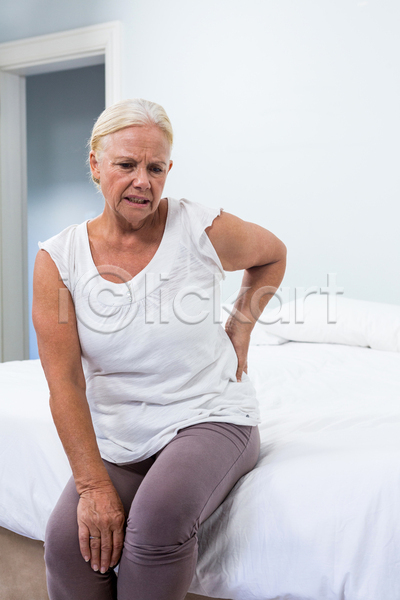 고통 60대 노년 백인 여자 한명 JPG 포토 해외이미지 건강 내려보기 문 백발 실내 앉기 은퇴 이불 주택 질병 찡그림 침대 침실 터치 해로움 해외202105 환자