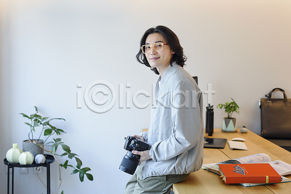 휴식 30대 남자 성인 성인남자한명만 한국인 한명 JPG 옆모습 포토 걸터앉기 들기 맨라이프 미소(표정) 사진사 상반신 실내 싱글라이프 안경낌 응시 재택근무 책상 카메라 프리랜서