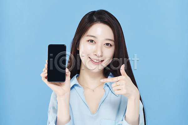청순 20대 성인 성인여자한명만 여자 한국인 한명 JPG 앞모습 포토 가리킴 들기 미소(표정) 뷰티 상반신 셔츠 스마트폰 스튜디오촬영 실내 응시 의료성형뷰티 차분 파란배경
