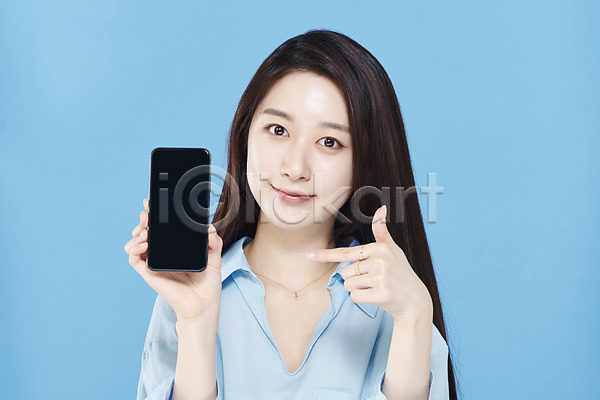 청순 20대 성인 성인여자한명만 여자 한국인 한명 JPG 앞모습 포토 가리킴 들기 미소(표정) 뷰티 상반신 셔츠 스마트폰 스튜디오촬영 실내 응시 의료성형뷰티 차분 파란배경