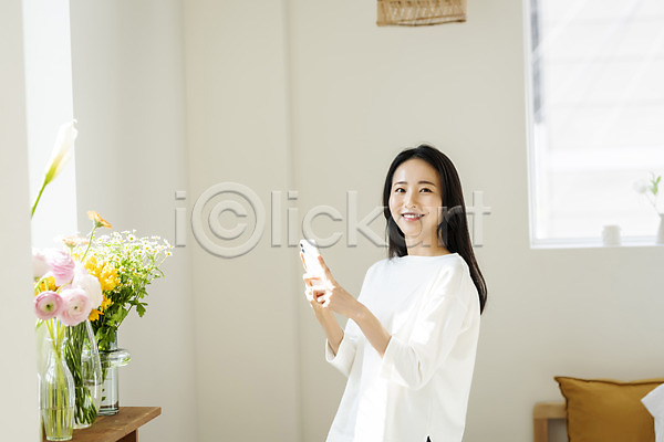 휴식 20대 성인 성인여자한명만 여자 한국인 한명 JPG 옆모습 포토 꽃 꽃병 들기 미소(표정) 뷰티 사진촬영 상반신 스마트폰 실내 싱글라이프 우먼라이프 응시 의료성형뷰티 창가