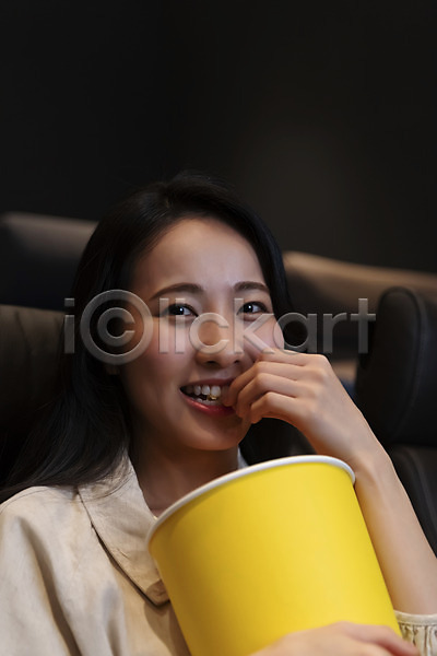 20대 성인 성인여자한명만 여자 한국인 한명 JPG 앞모습 포토 공공장소 들기 미소(표정) 상반신 실내 앉기 어둠 영화관 응시 팝콘 혼영