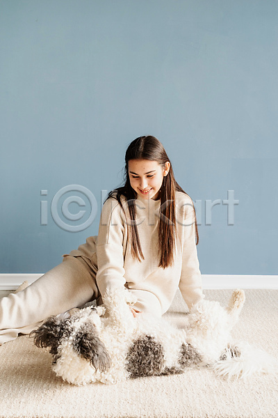 백인 성인 성인여자한명만 여자 한명 JPG 앞모습 포토 해외이미지 강아지 놀이 미소(표정) 믹스견 상반신 실내 쓰다듬기 앉기 응시 주택 카펫 한마리