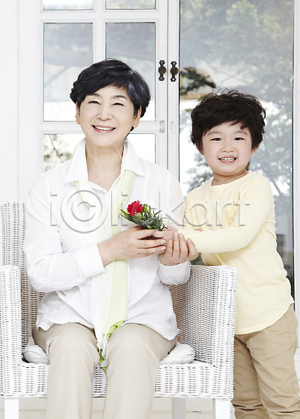 행복 화목 60대 남자 노년 동양인 두명 사람 성인 소년 어린이 여자 한국인 JPG 앞모습 포토 가족 기념일 꽃 라이프스타일 미소(표정) 서기 손자 식물 실내 앉기 어버이날 웃음 의자 주간 주기 창문 카네이션 할머니 효도