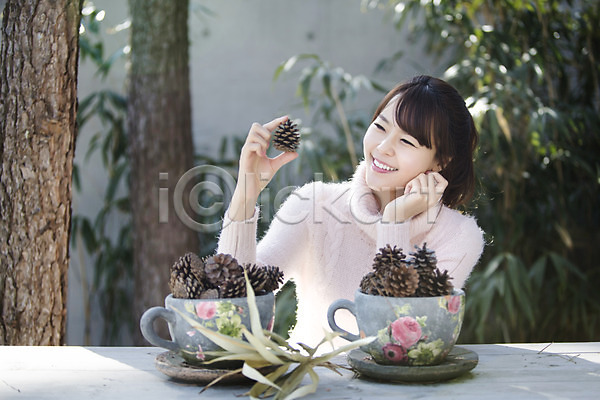 20대 동양인 사람 성인 성인여자한명만 여자 청년만 청년여자만 청년여자한명만 한국인 한명 JPG 앞모습 포토 들기 라이프스타일 모션 미소(표정) 상반신 솔방울 앉기 야외 우먼라이프 주간 컵 탁자