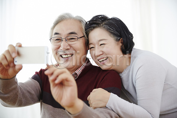 다정 60대 남자 노년 노인만 두명 여자 한국인 JPG 앞모습 포토 노부부 들기 미소(표정) 상반신 스마트폰 스튜디오촬영 실내 실버라이프 앉기 할머니 할아버지
