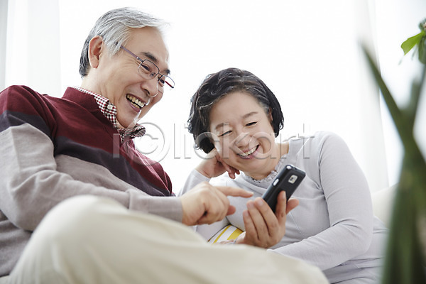 다정 60대 남자 노년 노인만 두명 여자 한국인 JPG 앞모습 포토 노부부 들기 미소(표정) 상반신 소파 스마트폰 스튜디오촬영 실내 실버라이프 앉기 할머니 할아버지