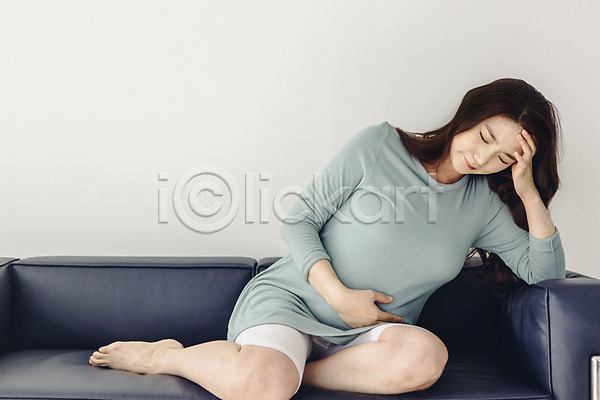 고통 괴로움 불쾌함 20대 성인 성인여자한명만 여자 청년여자한명만 한국인 한명 JPG 앞모습 포토 눈감음 맨발 소파 실내 앉기 임산부 임신 전신 진통 찡그림