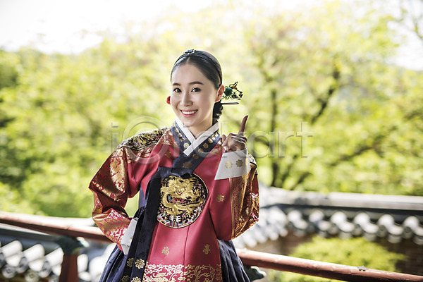 30대 성인 성인여자만 여자 한국인 한명 JPG 앞모습 포토 가리킴 기와담장 나무 미소(표정) 사극 상반신 야외 여왕 왕족전통의상 전통 조선시대 주간 한복
